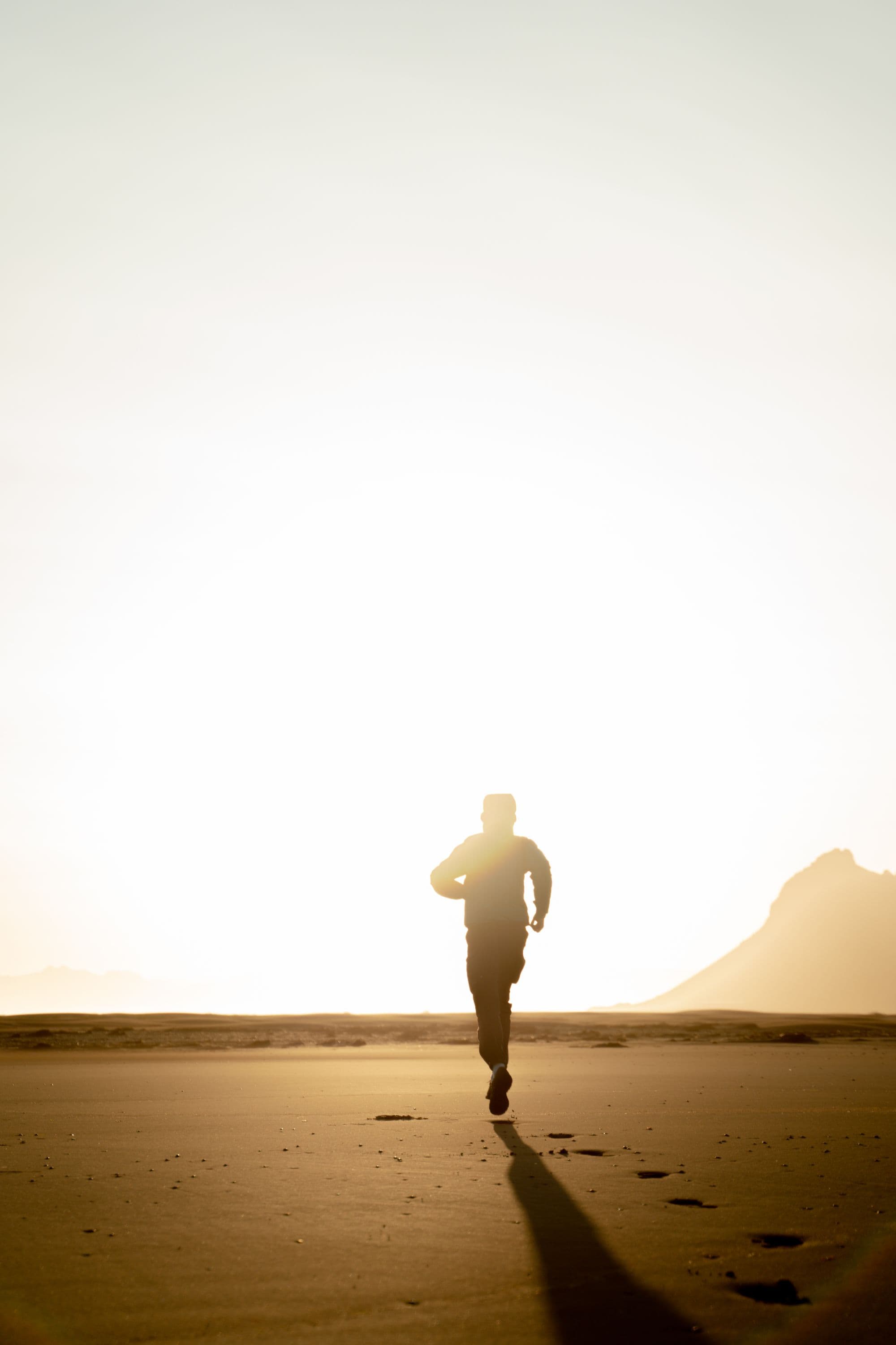 Man running along the shoreline at sunrise